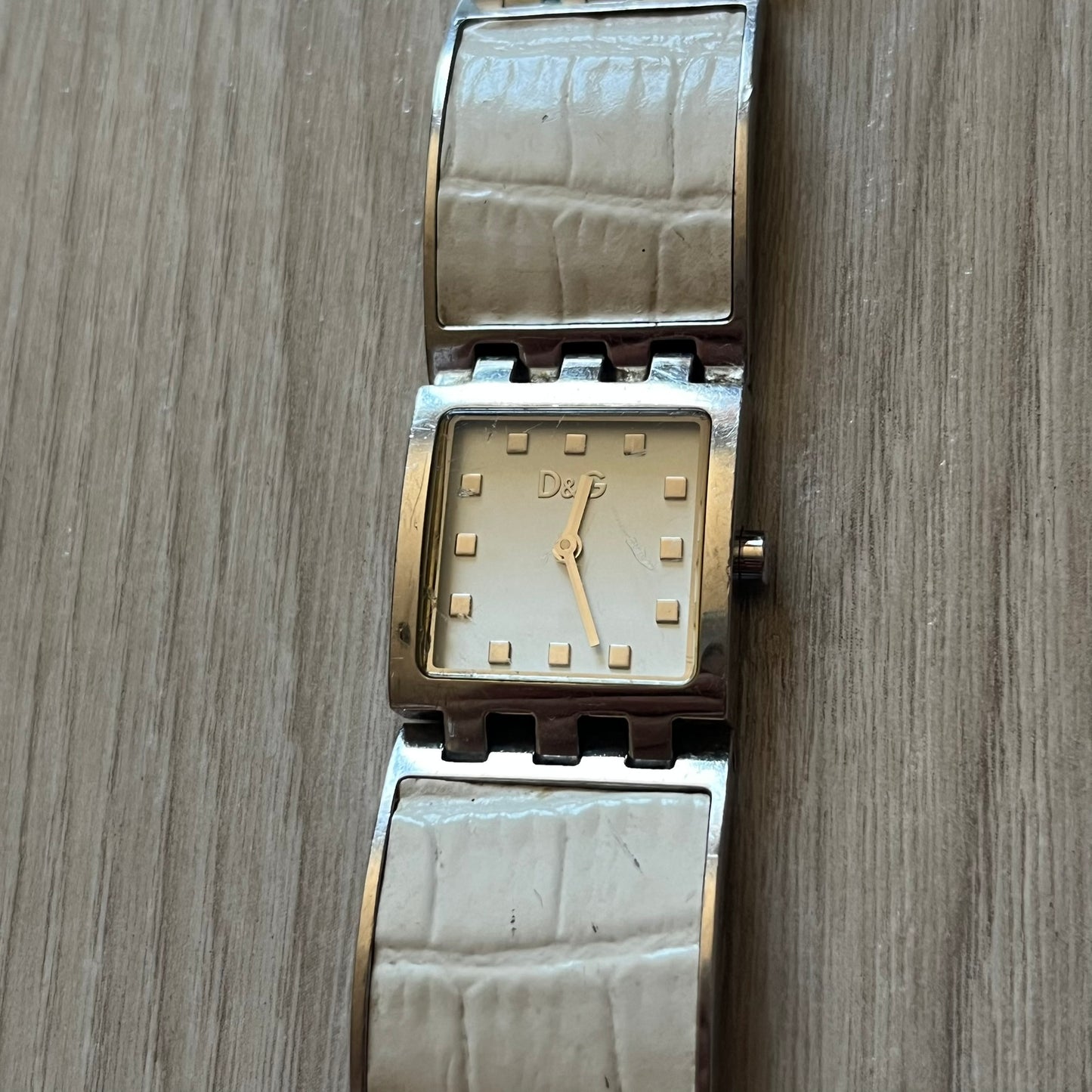 Dolce &amp; Gabbana white analog watch with a silver bracelet featuring white leather-like panels. The case seamlessly aligns with the width of the bracelet for a sleek, integrated look. A refined statement piece blending luxury design with modern elegance.