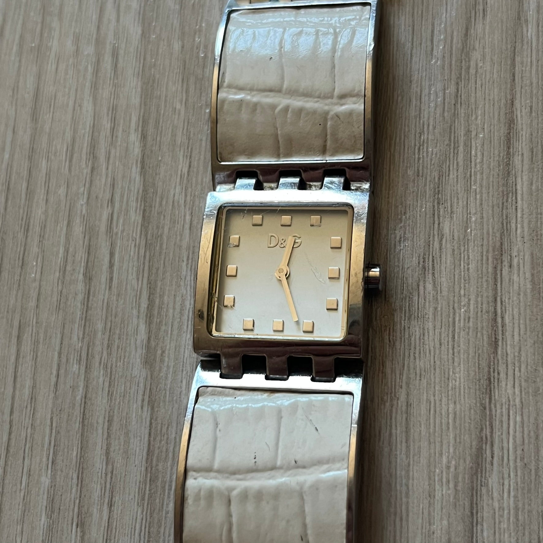 Dolce &amp; Gabbana white analog watch with a silver bracelet featuring white leather-like panels. The case seamlessly aligns with the width of the bracelet for a sleek, integrated look. A refined statement piece blending luxury design with modern elegance.