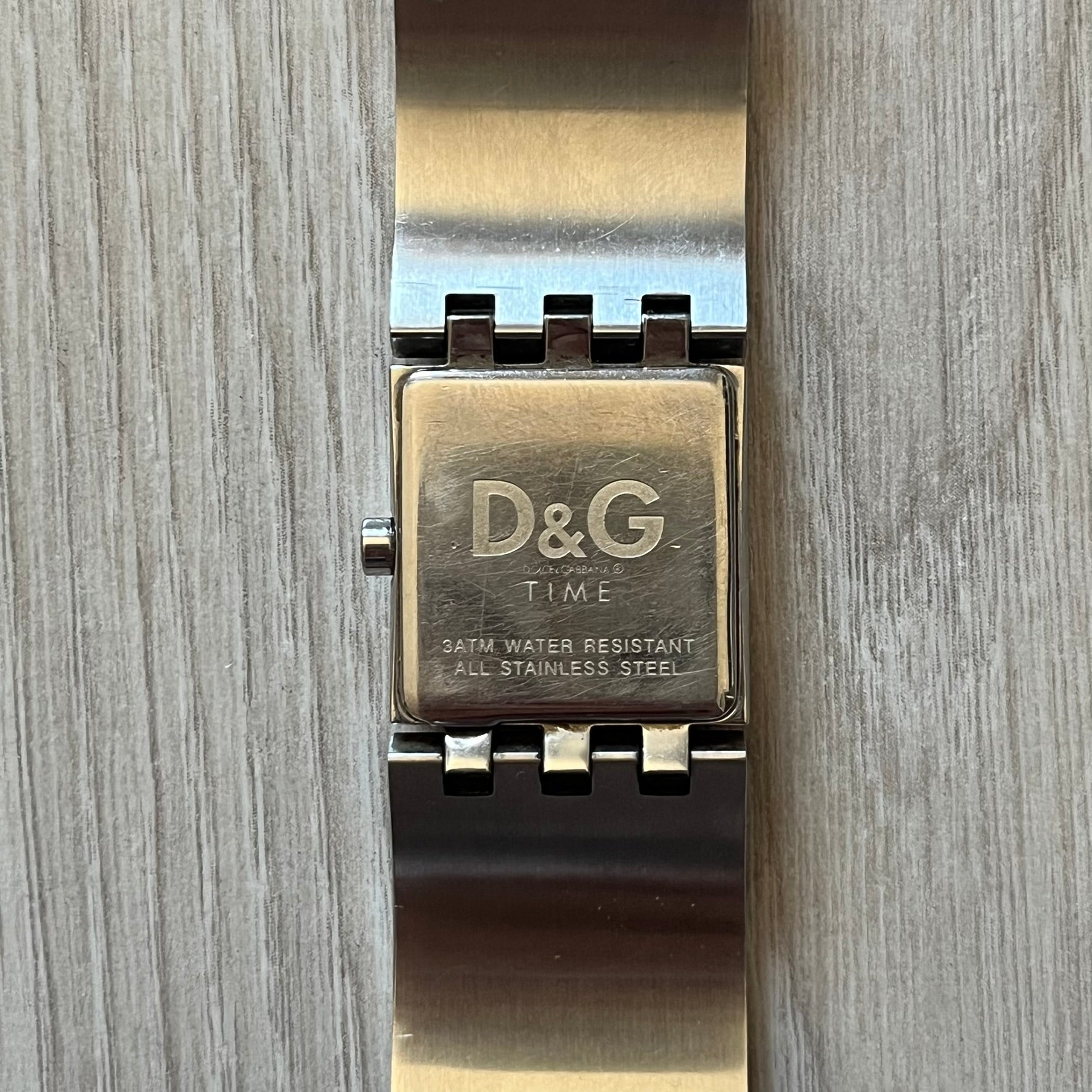 Dolce &amp; Gabbana white analog watch with a silver bracelet featuring white leather-like panels. The case seamlessly aligns with the width of the bracelet for a sleek, integrated look. A refined statement piece blending luxury design with modern elegance.