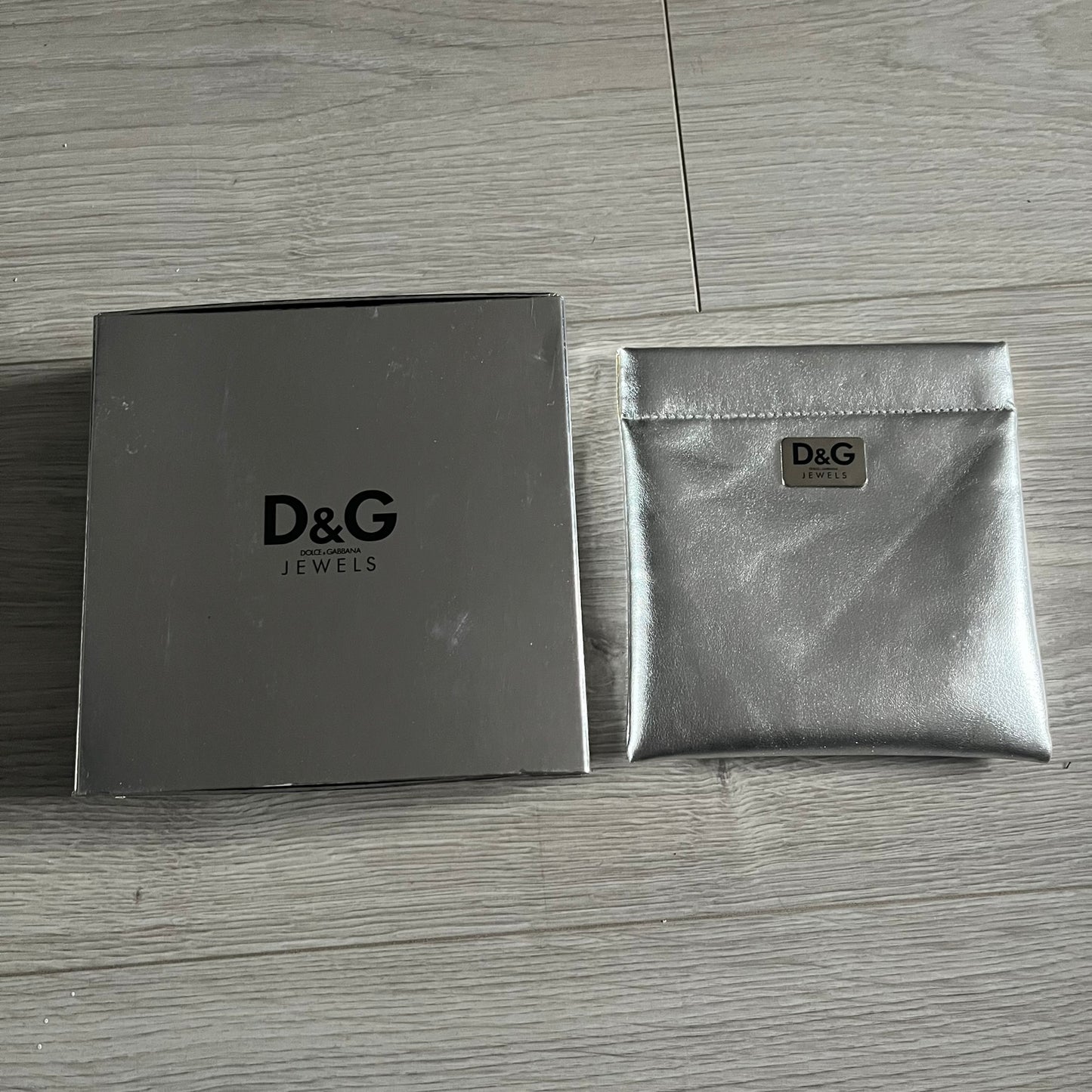 Dolce & Gabbana 7 Crosses Stainless Steel Choker Necklace. Crafted from polished stainless steel, this necklace features seven dangling crosses in varying designs, including full metal, black stones, white stones, and cut-out styles. One section of the chain incorporates a D&G logo in place of links. Comes with original box and dustbag.