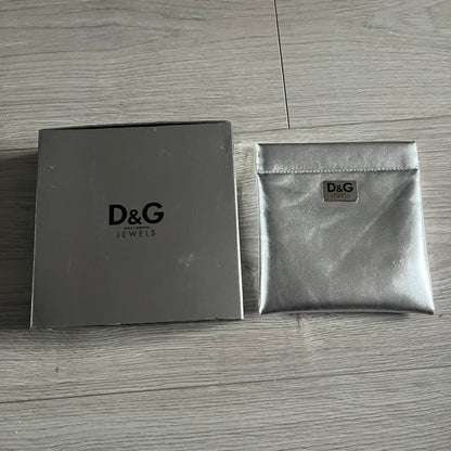 Dolce & Gabbana 7 Crosses Stainless Steel Choker Necklace. Crafted from polished stainless steel, this necklace features seven dangling crosses in varying designs, including full metal, black stones, white stones, and cut-out styles. One section of the chain incorporates a D&G logo in place of links. Comes with original box and dustbag.