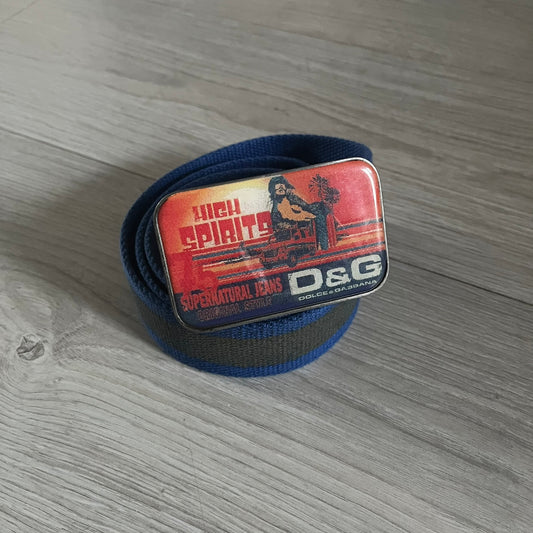 Dolce &amp; Gabbana “High Spirits” Fabric Belt in blue with a brown/gray central stripe and enamel-finished metal buckle. The buckle features vintage iconography and “High Spirits” lettering in vivid orange/red and navy tones. A rare 2000s-era Dolce &amp; Gabbana belt showcasing the brand’s early denim aesthetic.