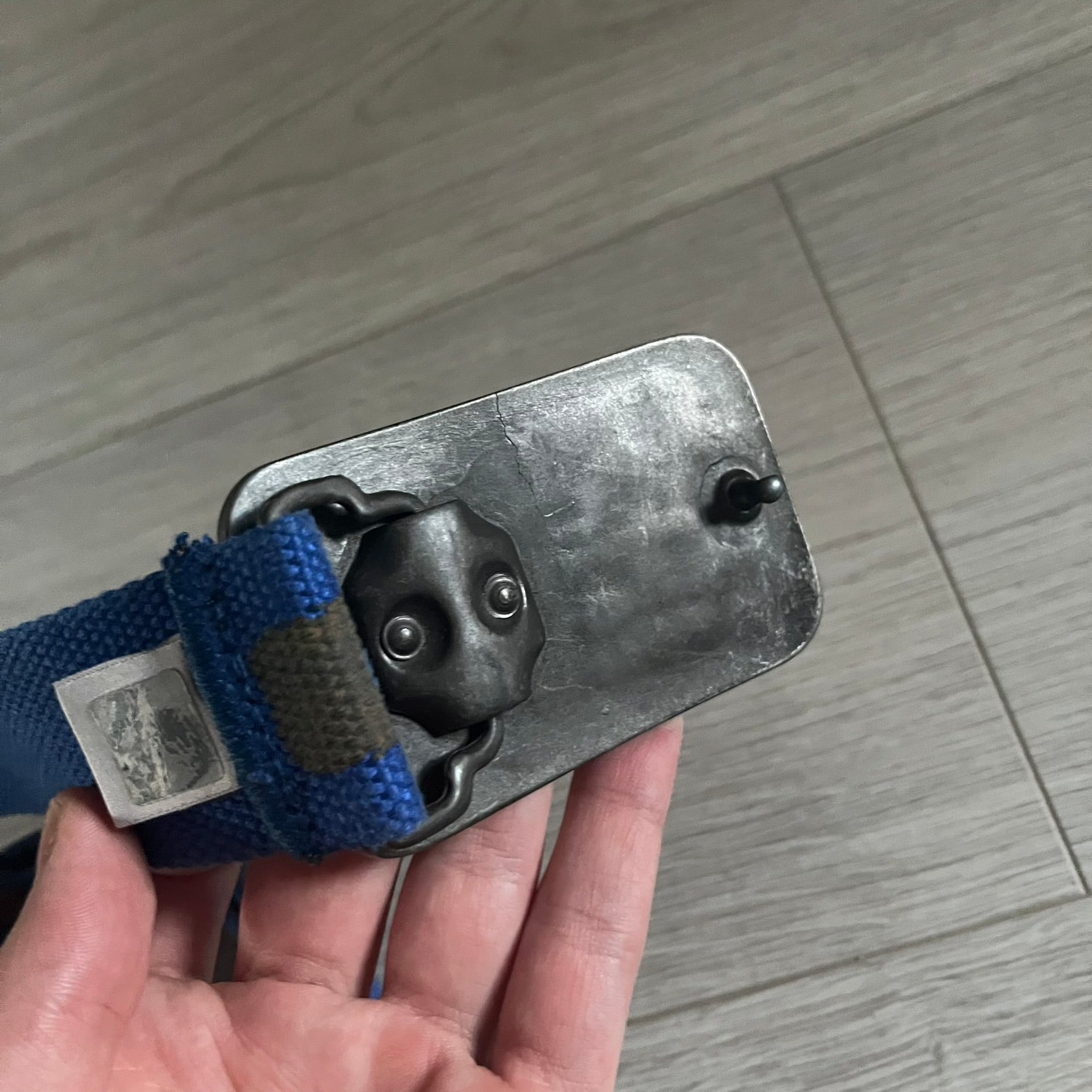 Dolce &amp; Gabbana “High Spirits” Fabric Belt in blue with a brown/gray central stripe and enamel-finished metal buckle. The buckle features vintage iconography and “High Spirits” lettering in vivid orange/red and navy tones. A rare 2000s-era Dolce &amp; Gabbana belt showcasing the brand’s early denim aesthetic.