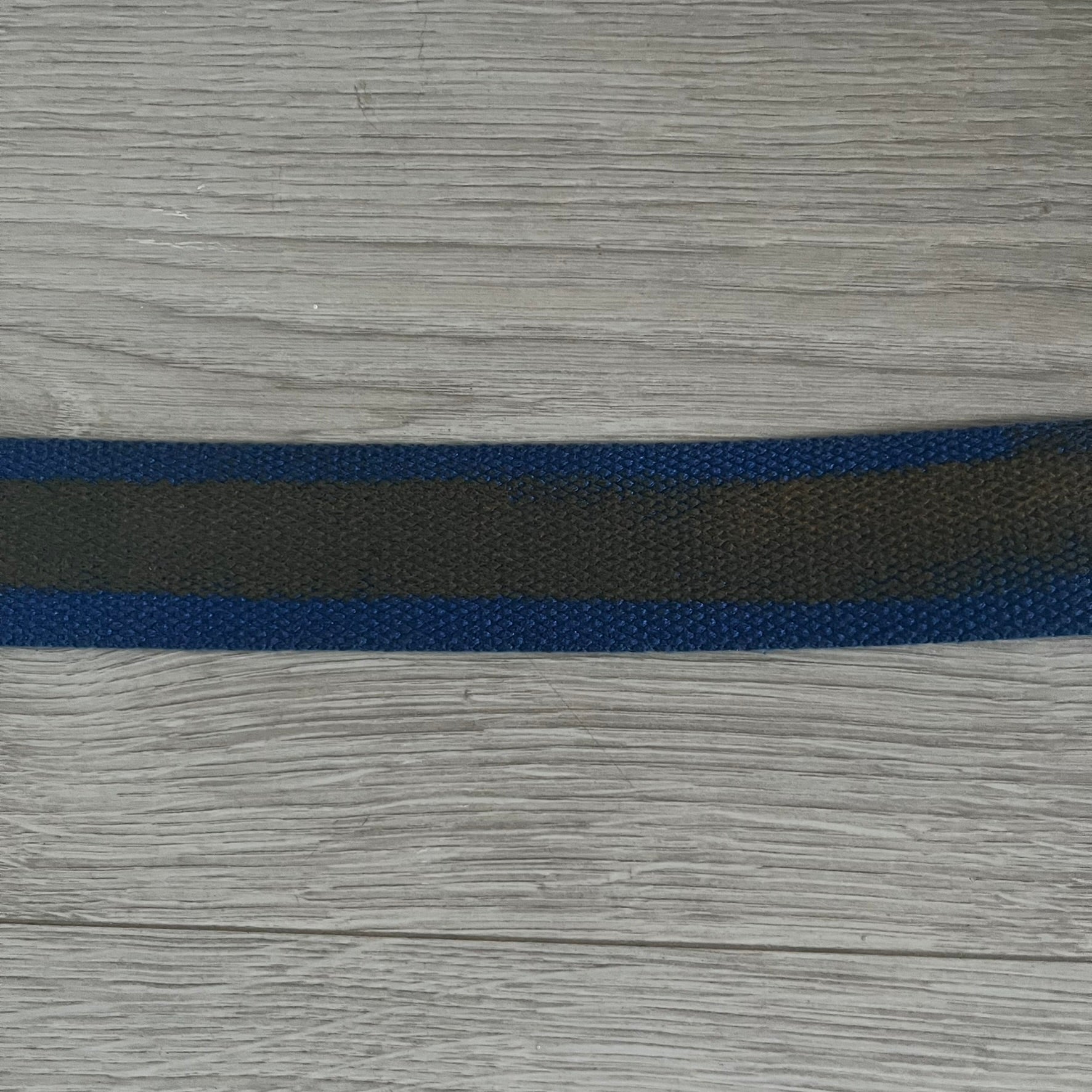 Dolce &amp; Gabbana “High Spirits” Fabric Belt in blue with a brown/gray central stripe and enamel-finished metal buckle. The buckle features vintage iconography and “High Spirits” lettering in vivid orange/red and navy tones. A rare 2000s-era Dolce &amp; Gabbana belt showcasing the brand’s early denim aesthetic.