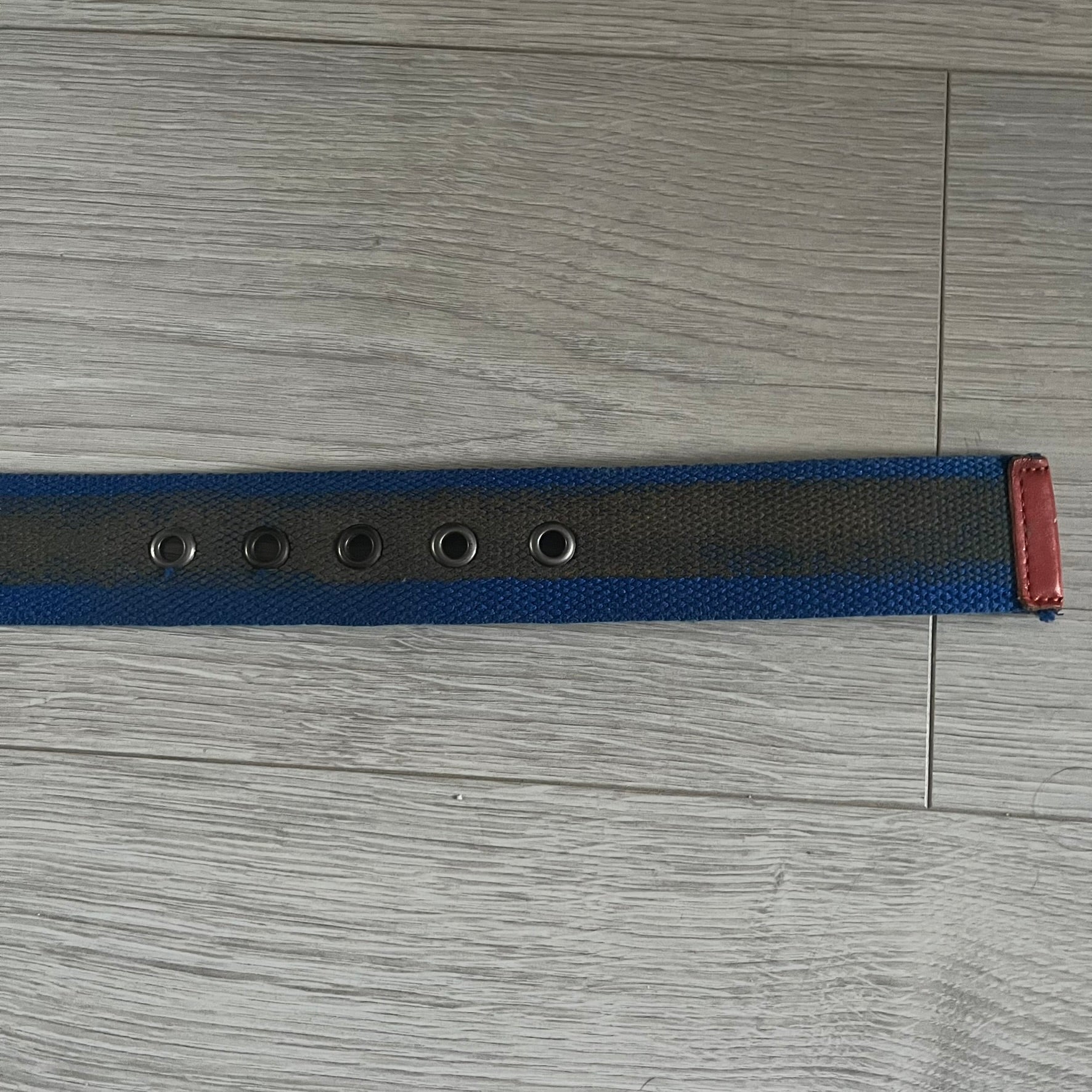 Dolce &amp; Gabbana “High Spirits” Fabric Belt in blue with a brown/gray central stripe and enamel-finished metal buckle. The buckle features vintage iconography and “High Spirits” lettering in vivid orange/red and navy tones. A rare 2000s-era Dolce &amp; Gabbana belt showcasing the brand’s early denim aesthetic.
