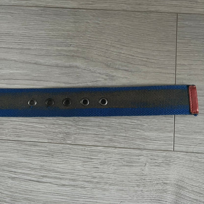 Dolce &amp; Gabbana “High Spirits” Fabric Belt in blue with a brown/gray central stripe and enamel-finished metal buckle. The buckle features vintage iconography and “High Spirits” lettering in vivid orange/red and navy tones. A rare 2000s-era Dolce &amp; Gabbana belt showcasing the brand’s early denim aesthetic.