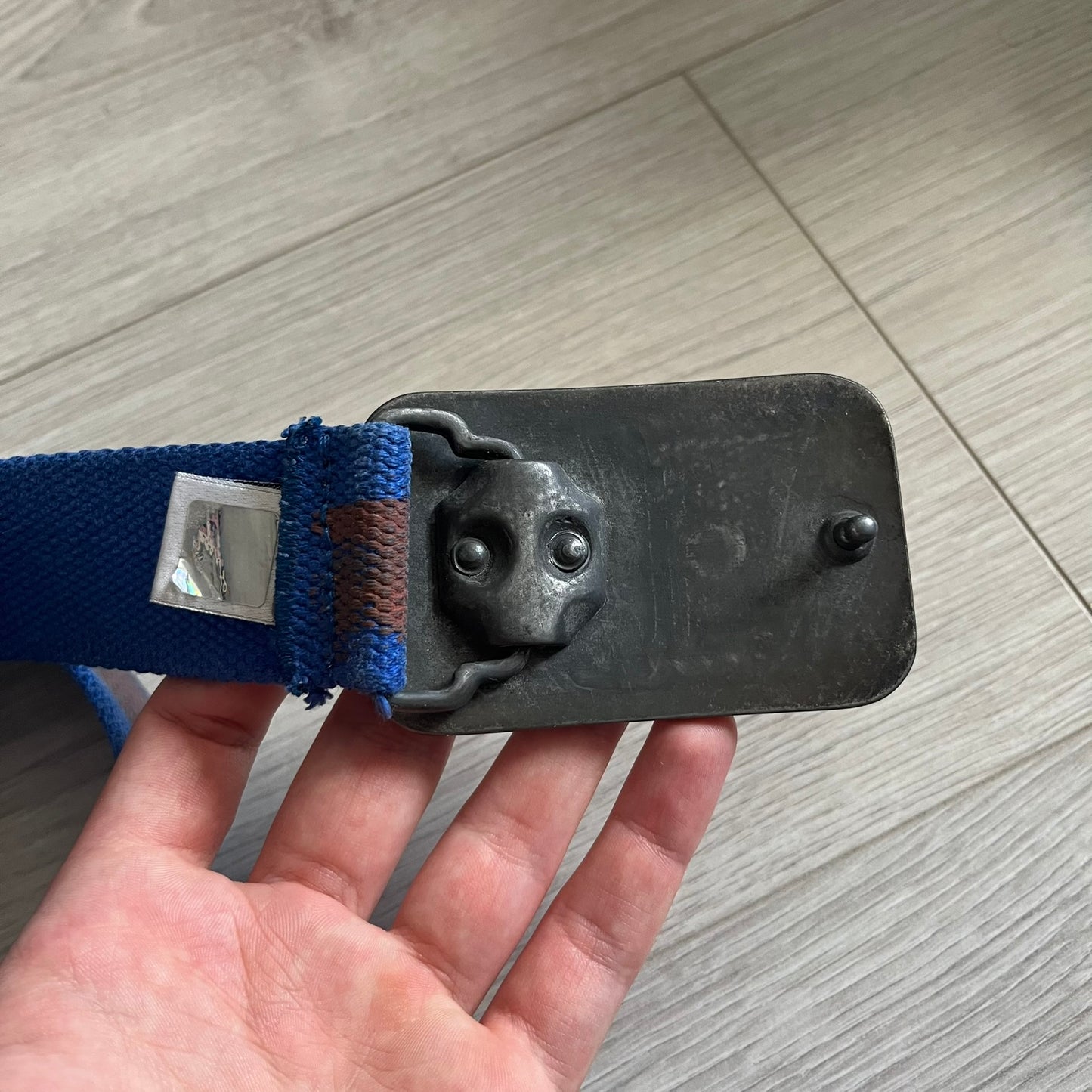 Dolce &amp; Gabbana “High Spirits” Fabric Belt in blue with a brown central stripe and enamel-finished metal buckle. The buckle features vintage iconography and “High Spirits” lettering in vivid orange/red and navy tones. A rare 2000s-era Dolce &amp; Gabbana belt showcasing the brand’s early denim aesthetic.