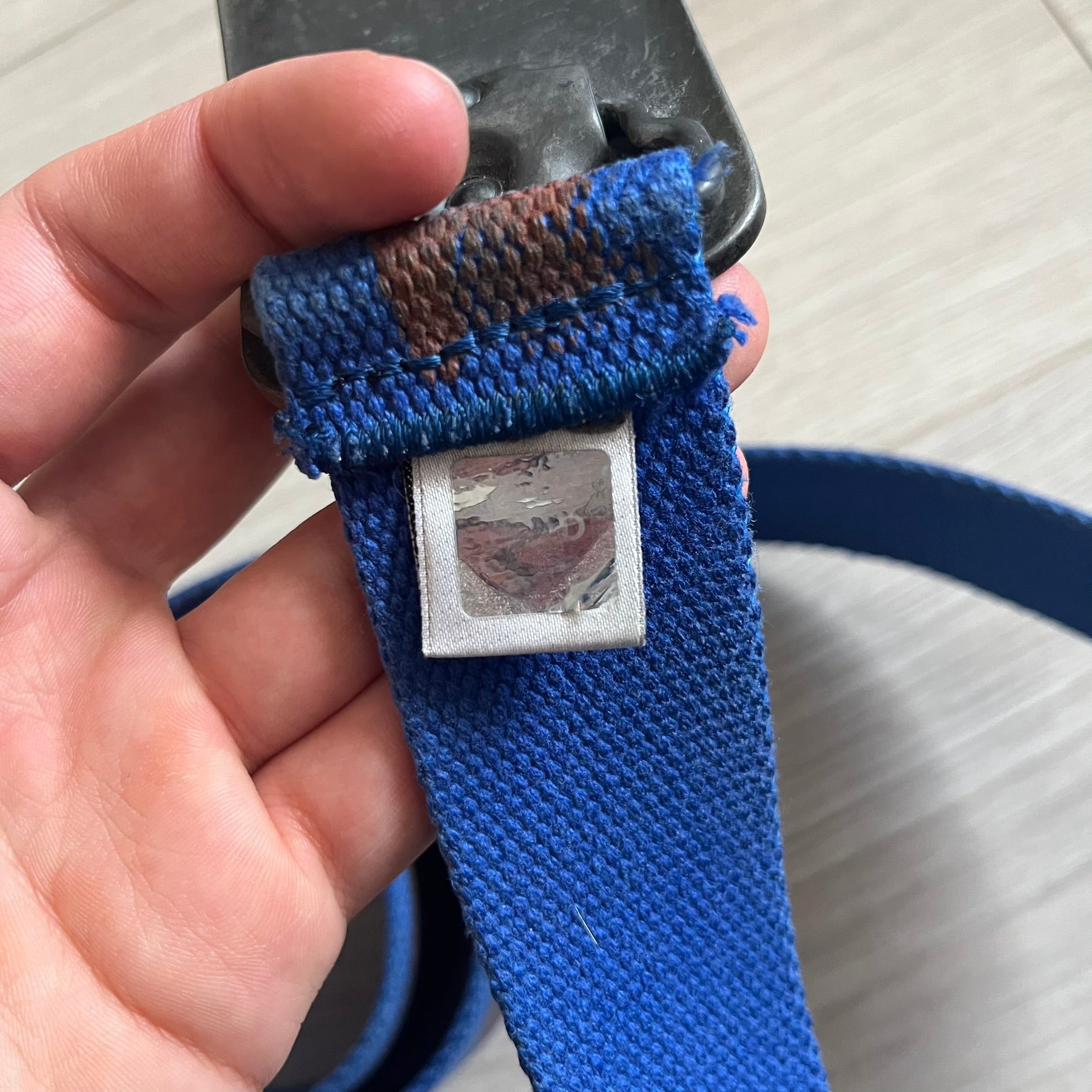 Dolce &amp; Gabbana “High Spirits” Fabric Belt in blue with a brown central stripe and enamel-finished metal buckle. The buckle features vintage iconography and “High Spirits” lettering in vivid orange/red and navy tones. A rare 2000s-era Dolce &amp; Gabbana belt showcasing the brand’s early denim aesthetic.