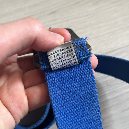 Dolce &amp; Gabbana “High Spirits” Fabric Belt in blue with a brown central stripe and enamel-finished metal buckle. The buckle features vintage iconography and “High Spirits” lettering in vivid orange/red and navy tones. A rare 2000s-era Dolce &amp; Gabbana belt showcasing the brand’s early denim aesthetic.