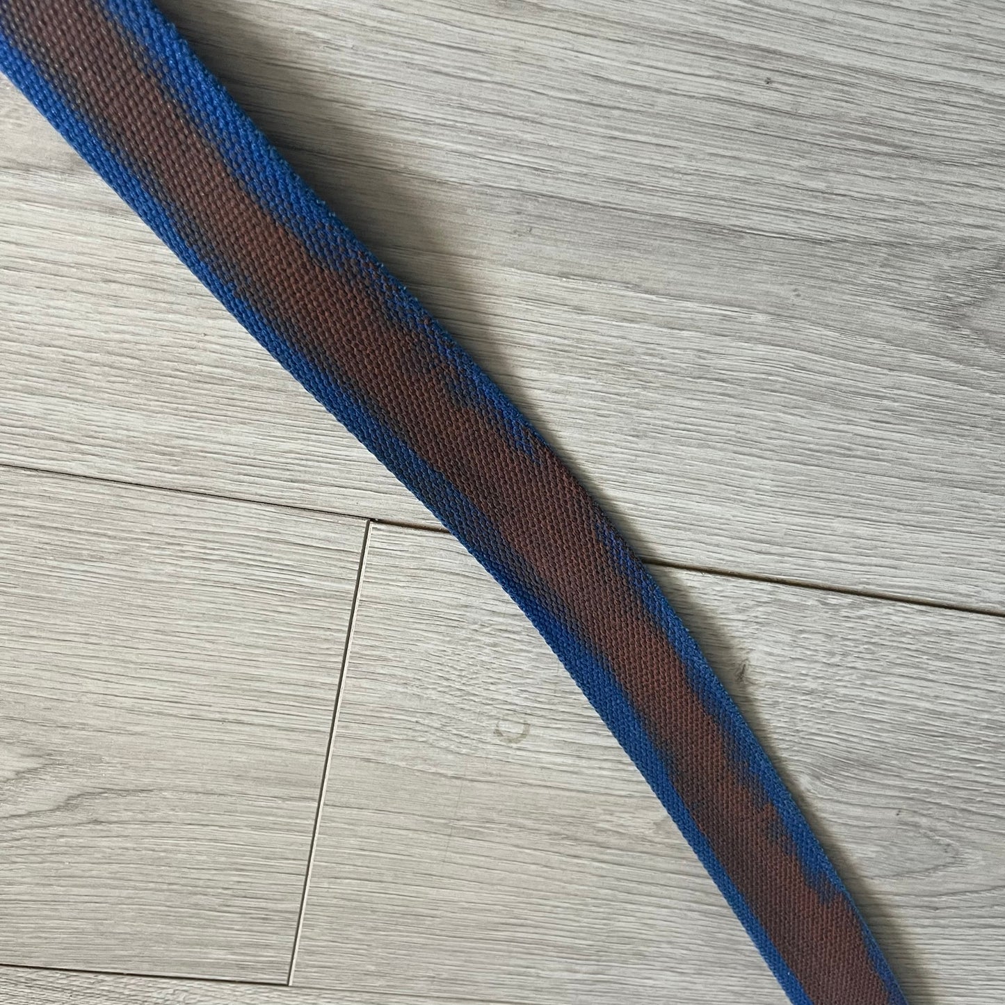 Dolce &amp; Gabbana “High Spirits” Fabric Belt in blue with a brown central stripe and enamel-finished metal buckle. The buckle features vintage iconography and “High Spirits” lettering in vivid orange/red and navy tones. A rare 2000s-era Dolce &amp; Gabbana belt showcasing the brand’s early denim aesthetic.