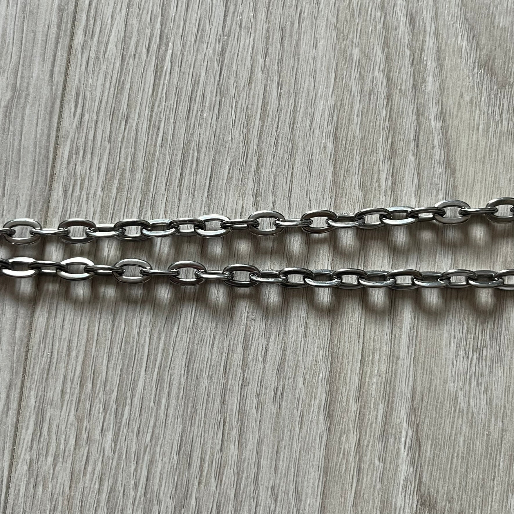 Dolce & Gabbana 'Unclassifiable' Dog Tag Necklace in stainless steel with a silver cable chain and lobster clasp. Features a thick dog tag with four visible screws on the front and engraved D& G logo with “Unclassifiable” diagonally beneath.