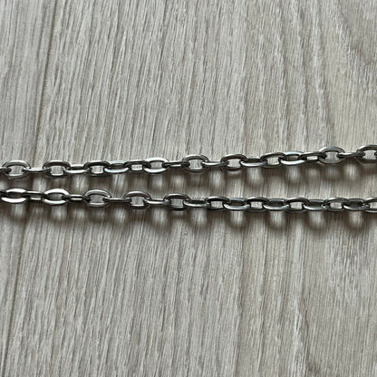 Dolce & Gabbana 'Unclassifiable' Dog Tag Necklace in stainless steel with a silver cable chain and lobster clasp. Features a thick dog tag with four visible screws on the front and engraved D& G logo with “Unclassifiable” diagonally beneath.