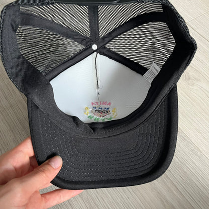 Drake Anita Max Wynn Pink Trucker Hat in all-black front panel, sides and cap, featuring a collection of graphics including a woman with an oversized head, two yellow dollar signs, and “ANITA” in pink, “MAX” in blue, and “WYNN” in green. Designed with a mesh back for breathability, a snapback closure for adjustability, and polyester construction to keep the head cool. A playful tribute to Drake’s alter ego and love of g4mbling.