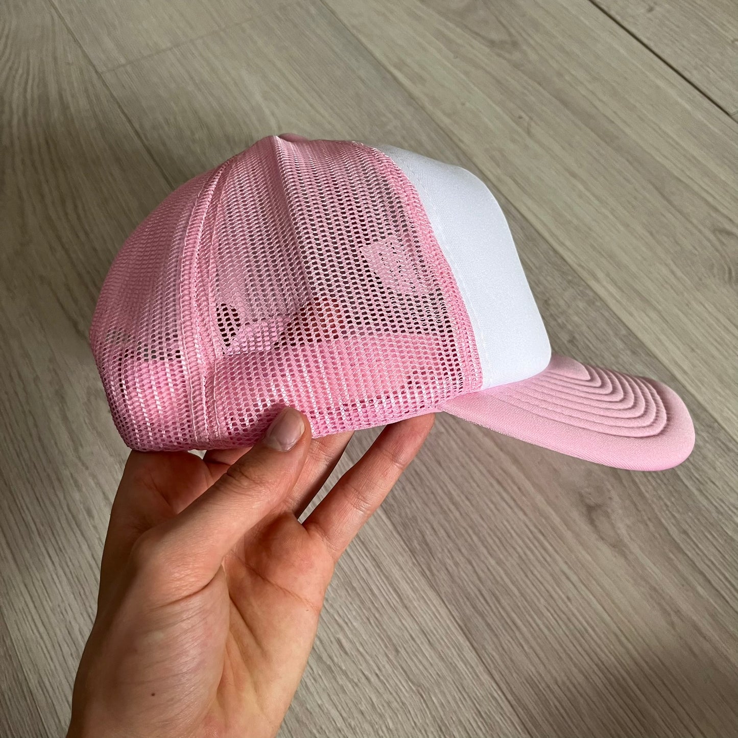 The Drake Anita Max Wynn Hat Punk is a trucker hat that pays tribute to hip-hop artist Drake’s alter ego, Anita Max Wynn. Pink sides and cap, white front.
The hat was inspired by Drake’s love of gambling and his need to get a "max win." The details include a collection of graphics on the front, such as a woman with an oversized head and a pink jacket, two yellow dollar signs, "ANITA" in pink, "MAX" in Blue, and " WYNN" in green. The hat features an construction with a mesh back. A traditional snapback provi