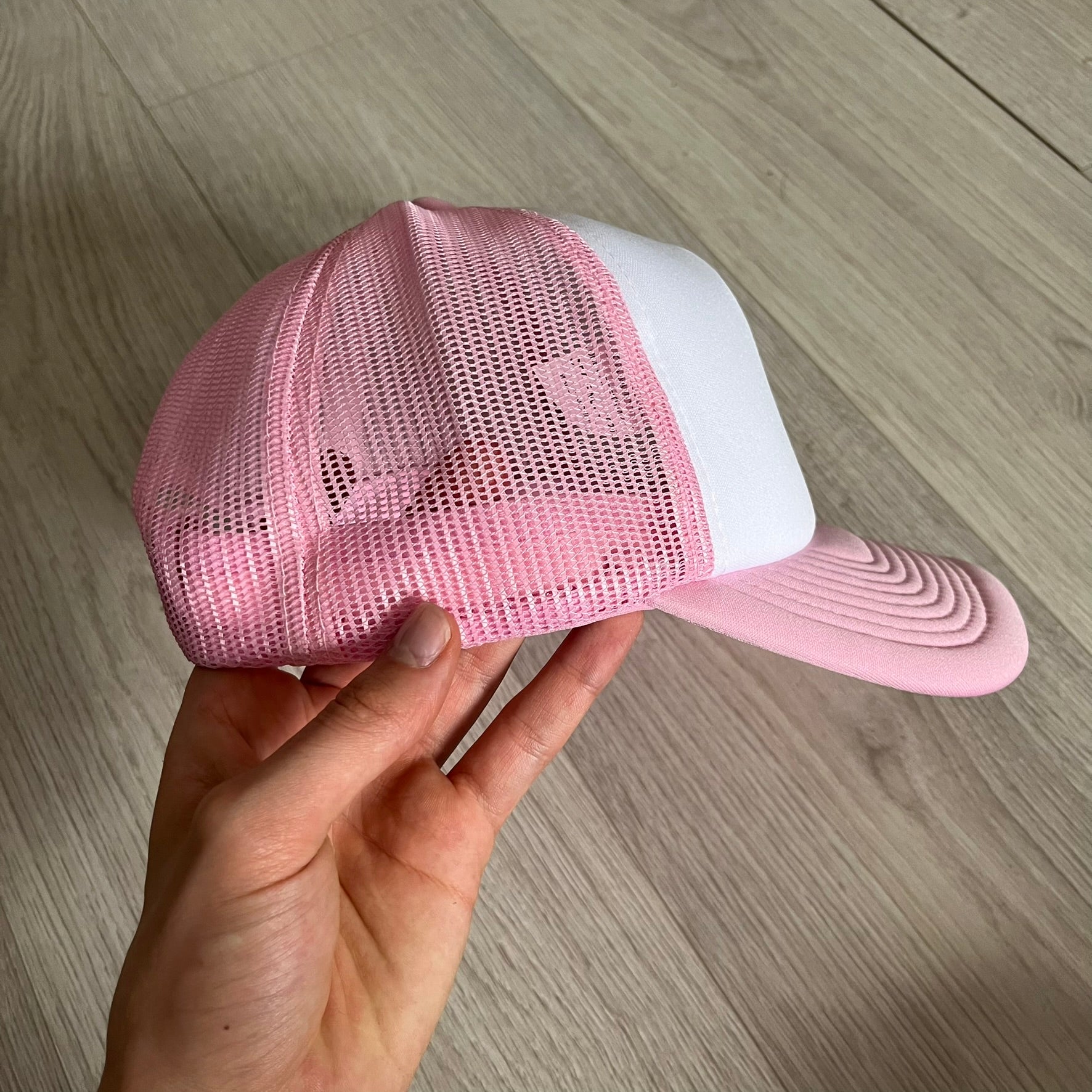 The Drake Anita Max Wynn Hat Punk is a trucker hat that pays tribute to hip-hop artist Drake’s alter ego, Anita Max Wynn. Pink sides and cap, white front.
The hat was inspired by Drake’s love of gambling and his need to get a "max win." The details include a collection of graphics on the front, such as a woman with an oversized head and a pink jacket, two yellow dollar signs, "ANITA" in pink, "MAX" in Blue, and " WYNN" in green. The hat features an construction with a mesh back. A traditional snapback provi