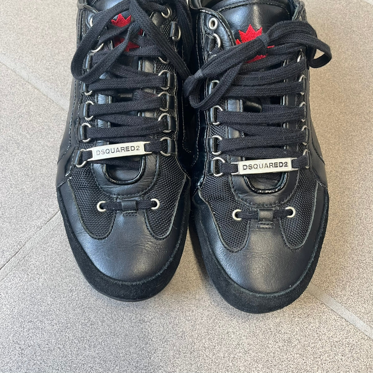 Dsquared2 2010's Multi Fabric Legendary Sneakers are constructed from tonal velvet, patent leather, metal eyelets and a woven rubber sole. They feature a red embroidered Canadian leaf on the tongue, a metal Dsquared2 plaque at the base of the laces, and an embroidered black Dsquared2 logo.