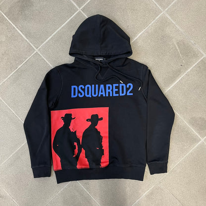 Dsquared2 2017 Western Cowboys Hoodie is a black hoodie featuring a blue Dsquared2 text logo across the upper front and a red square graphic on the lower right. Inside the square are two black cowboy figures wearing hats. The hoodie was made in Portugal.
