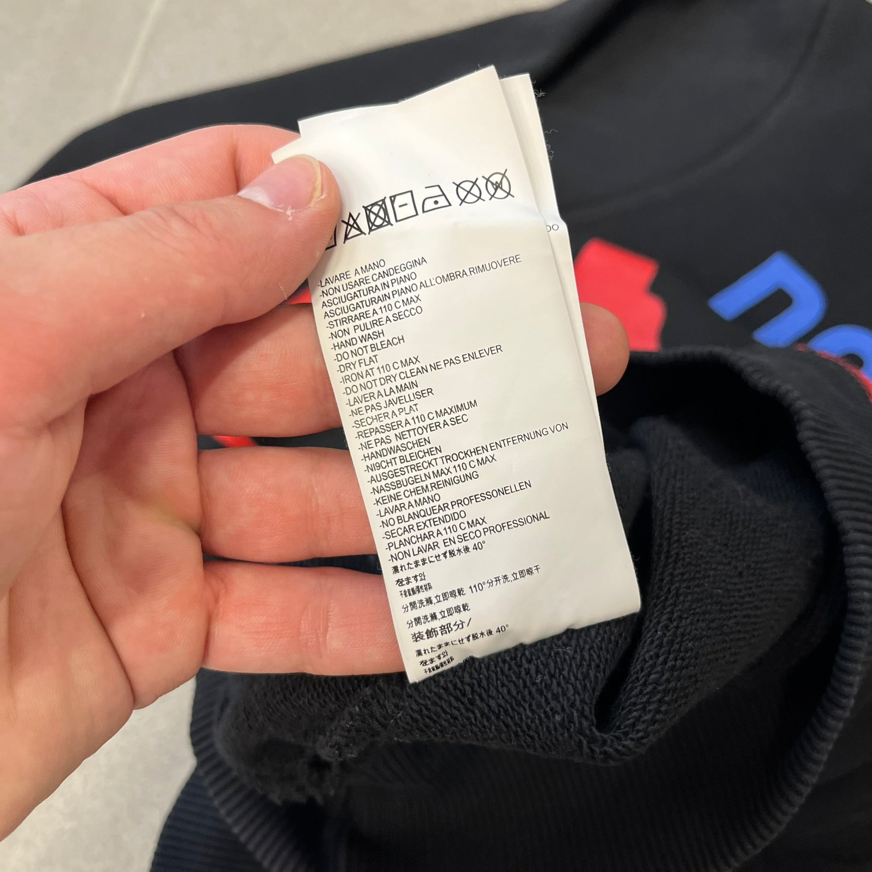 Dsquared2 2017 Western Cowboys Hoodie is a black hoodie featuring a blue Dsquared2 text logo across the upper front and a red square graphic on the lower right. Inside the square are two black cowboy figures wearing hats. The hoodie was made in Portugal.

