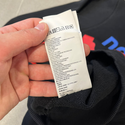 Dsquared2 2017 Western Cowboys Hoodie is a black hoodie featuring a blue Dsquared2 text logo across the upper front and a red square graphic on the lower right. Inside the square are two black cowboy figures wearing hats. The hoodie was made in Portugal.

