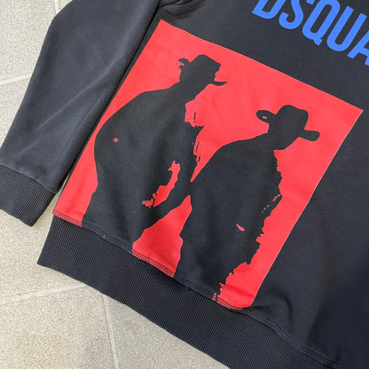 Dsquared2 2017 Western Cowboys Hoodie is a black hoodie featuring a blue Dsquared2 text logo across the upper front and a red square graphic on the lower right. Inside the square are two black cowboy figures wearing hats. The hoodie was made in Portugal.
