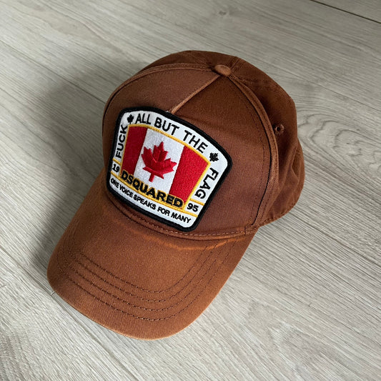Brown cap with a patch featuring a Canadian flag and text on a wooden surface