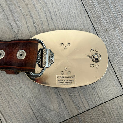 Dsquared2 Big Navy Plaque Leather Belt is a leather belt featuring a large oval metal buckle with a silver-tone frame and navy enamel center. The buckle displays DSQUARED2 text in the middle, while the strap includes stamped branding and product details. Made from brown leather, the belt is size small.