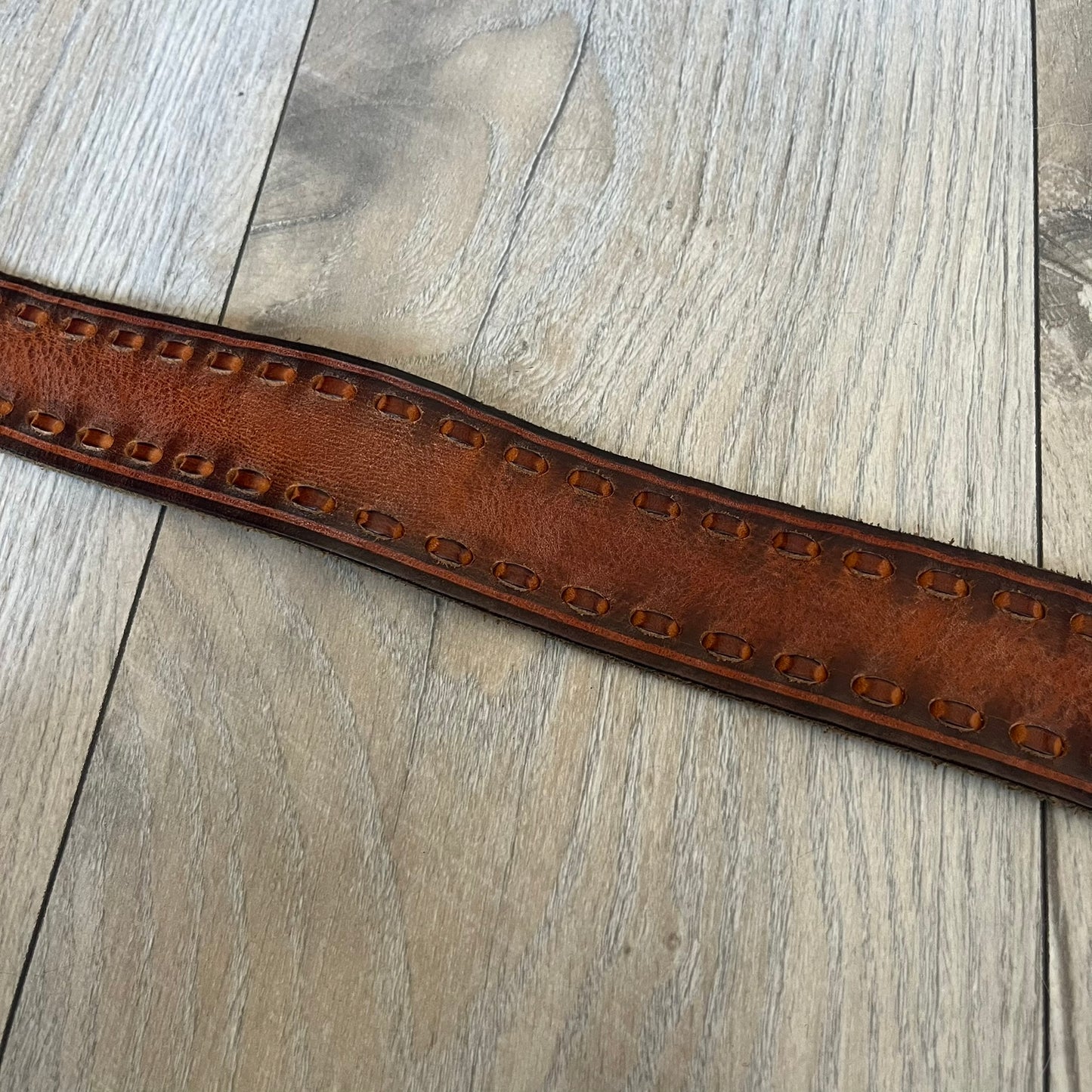 Dsquared2 Big Navy Plaque Leather Belt is a leather belt featuring a large oval metal buckle with a silver-tone frame and navy enamel center. The buckle displays DSQUARED2 text in the middle, while the strap includes stamped branding and product details. Made from brown leather, the belt is size small.