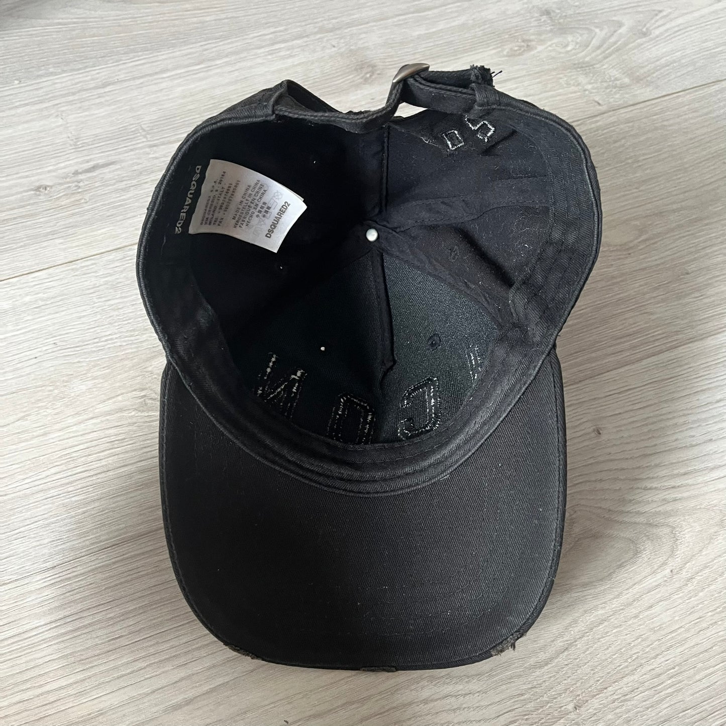 Black cap with brand logo on a light wooden surface