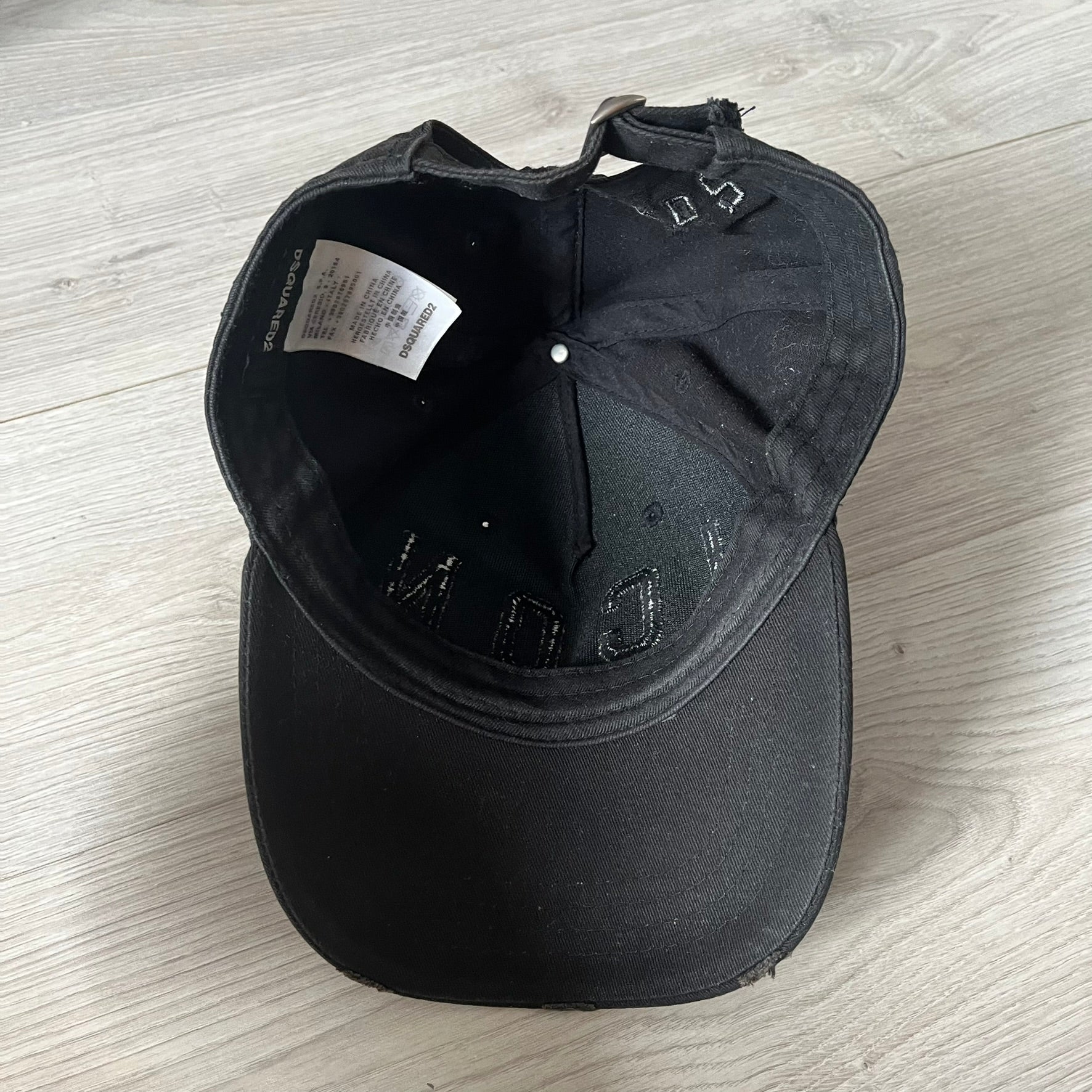 Black cap with brand logo on a light wooden surface
