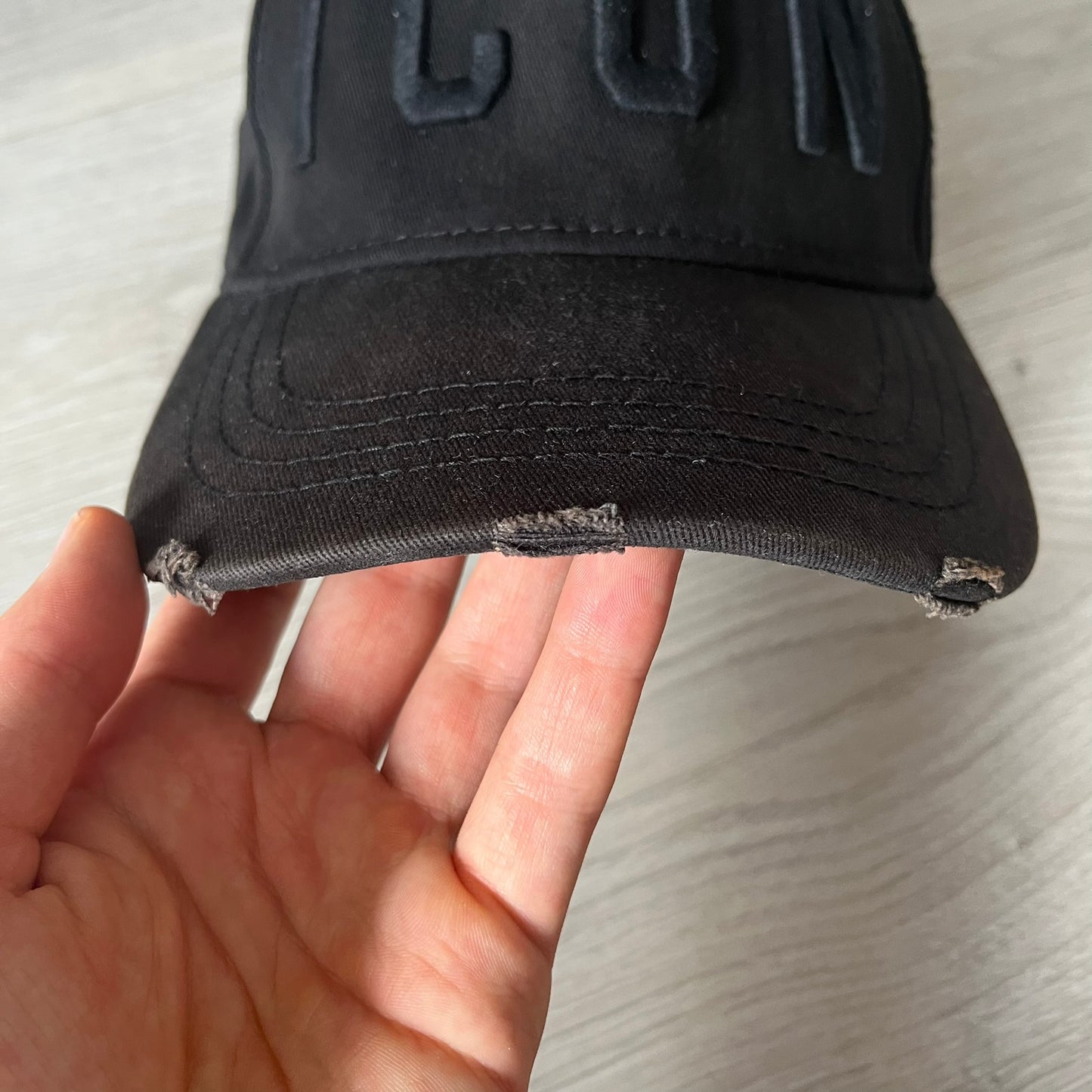 Black cap with 'CUB' branding held by a hand on a light background