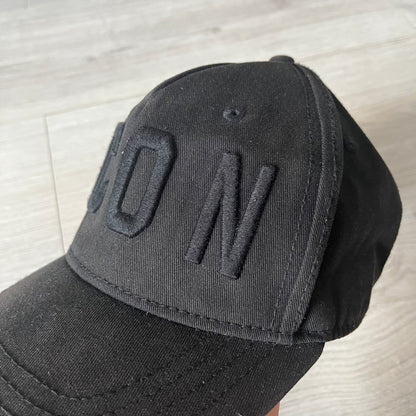 Black cap with 'DON' text on a light wooden surface