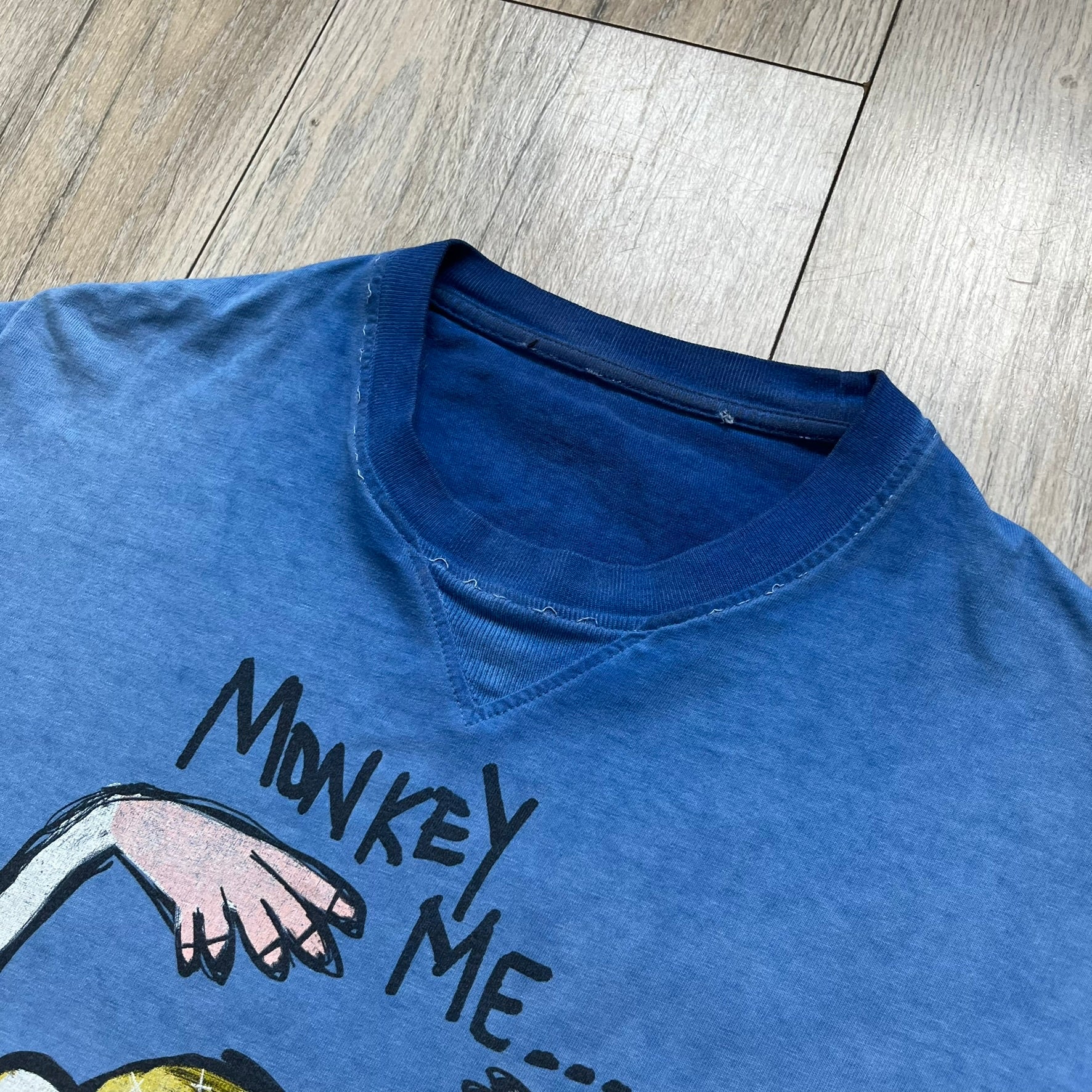 Dsquared2 Blue Rebel Monkey T-Shirt from the Spring/Summer 2015 collection. Crafted in Italy from cotton, the tee features a washed blue finish with darker tonal hems and a lighter faded center. The front displays a large stylized monkey graphic in yellow, white, red, and black, with text reading “Monkey Me… Dsquared2 Motherfuc…” incorporated into the design.