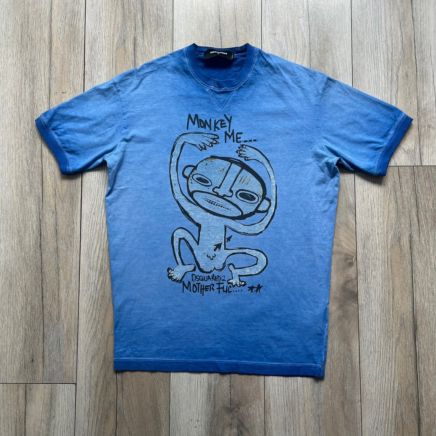 Dsquared2 Blue Rebel Monkey T-Shirt from the Spring/Summer 2015 collection. Crafted in Italy from cotton, the tee features a washed blue finish with darker tonal hems and a lighter faded center. The front displays a large stylized monkey graphic in black with light blue, with text reading “Monkey Me… Dsquared2 Motherfuc…” incorporated into the design.