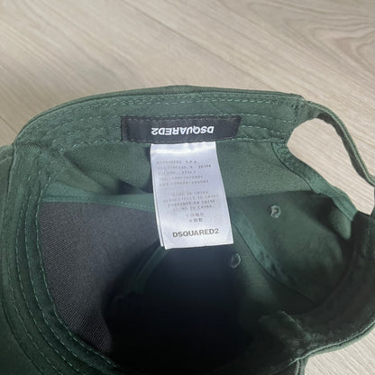 Green cap with Dsquared2 label on a light wooden surface