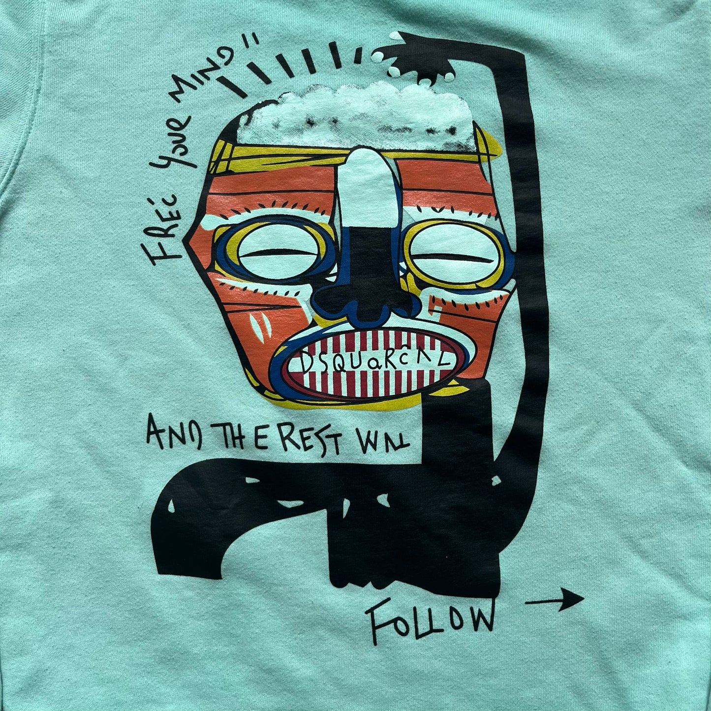 Dsquared2 SS2015 “Free Your Mind” Crewneck is a turquoise cotton sweatshirt with a washed, faded finish and tonal variation across the fabric. The front features a black Basquiat-inspired figure with “Free Your Mind and the Rest Will Follow” text in a contrasting design. The piece is made in Italy and includes darker tonal hems with a lighter center fade for a worn effect.&nbsp;