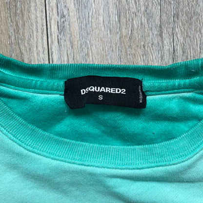 Dsquared2 SS2015 “Free Your Mind” Crewneck is a turquoise cotton sweatshirt with a washed, faded finish and tonal variation across the fabric. The front features a black Basquiat-inspired figure with “Free Your Mind and the Rest Will Follow” text in a contrasting design. The piece is made in Italy and includes darker tonal hems with a lighter center fade for a worn effect.&nbsp;