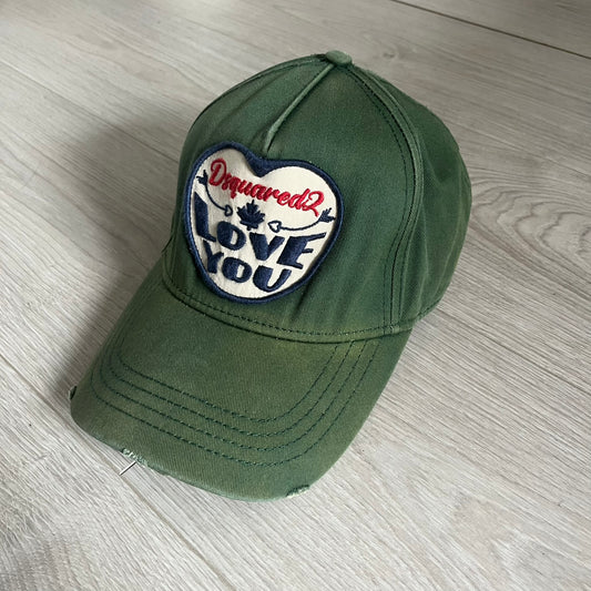 Green cap with a heart-shaped patch on a wooden surface