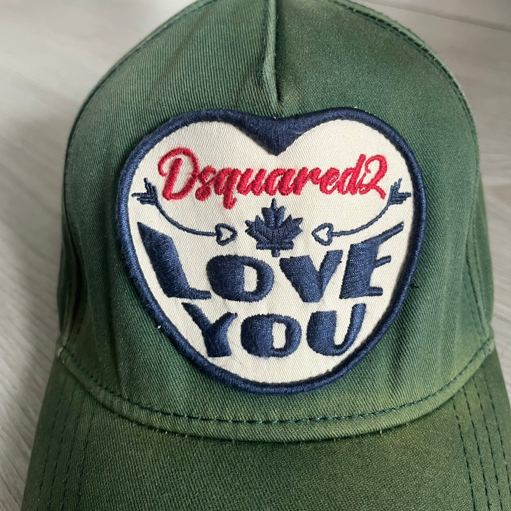 Green cap with a heart-shaped patch featuring 'Dsquared2 Love You' text on a white background