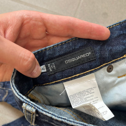 Dsquared2 SS2012 Mud Splash Jeans are runway bottoms from the Spring/Summer 2012 collection, made in Italy from 100% cotton. The jeans feature a deliberate two-tone design with a clean blue-denim upper section transitioning into a heavy brown “mud” effect on the lower half. They include branded buttons and rivets, a Dsquared2 back patch, and a small red maple leaf metal pin on the back pocket.