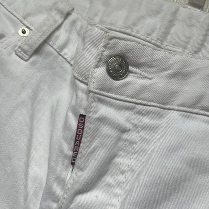 Dsquared2 SS2012 White Mud Jeans are runway pieces from the Spring/Summer 2012 collection, made in Italy from 98% cotton and 2% elastane. The jeans feature a deliberate two-tone design with a clean white upper section transitioning into a heavy brown “mud” effect on the lower half. They include branded buttons and rivets, a Dsquared2 front patch, and a small red maple leaf metal pin on the back pocket. The leg opening measures approximately 17 cm, with a slightly stretchy slim fit construction.