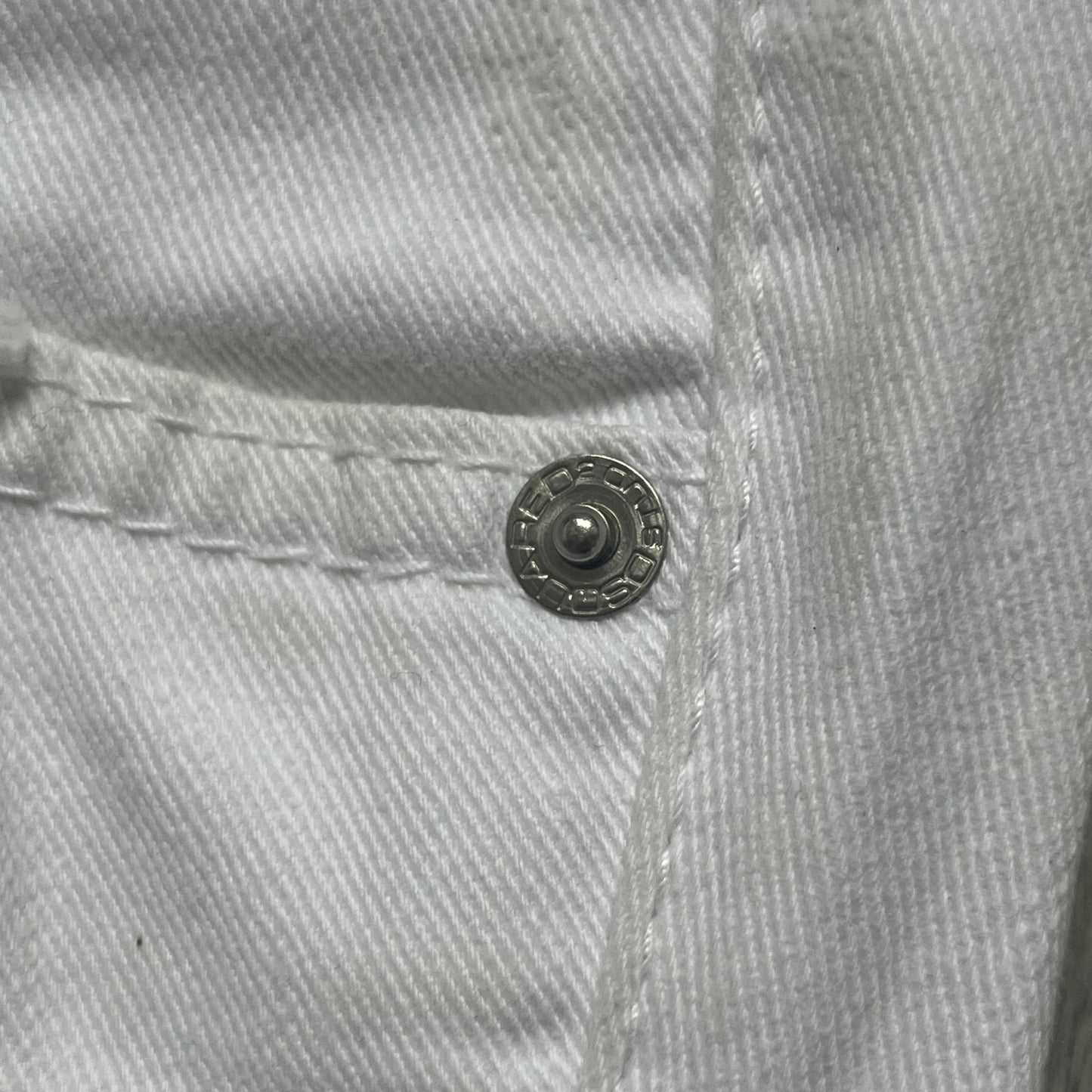 Dsquared2 SS2012 White Mud Jeans are runway pieces from the Spring/Summer 2012 collection, made in Italy from 98% cotton and 2% elastane. The jeans feature a deliberate two-tone design with a clean white upper section transitioning into a heavy brown “mud” effect on the lower half. They include branded buttons and rivets, a Dsquared2 front patch, and a small red maple leaf metal pin on the back pocket. The leg opening measures approximately 17 cm, with a slightly stretchy slim fit construction.