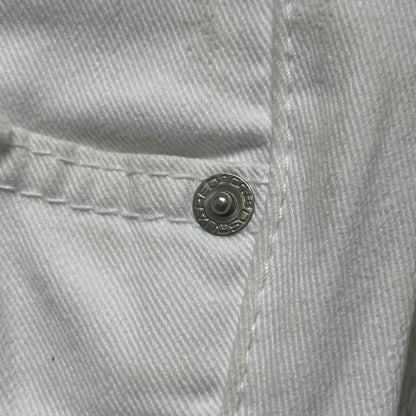 Dsquared2 SS2012 White Mud Jeans are runway pieces from the Spring/Summer 2012 collection, made in Italy from 98% cotton and 2% elastane. The jeans feature a deliberate two-tone design with a clean white upper section transitioning into a heavy brown “mud” effect on the lower half. They include branded buttons and rivets, a Dsquared2 front patch, and a small red maple leaf metal pin on the back pocket. The leg opening measures approximately 17 cm, with a slightly stretchy slim fit construction.