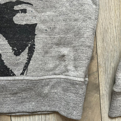 Dsquared2 Vicious Bros SS2019 Hoodie is a grey cotton hoodie made in Italy. It features a hood with drawstring fastening, long sleeves, and ribbed cuffs and hem. The front includes a printed graphic of two outlined figures with a small Dsquared2 logo and pink “Vicious Bros” text above them. The hoodie has intentional distressing throughout the fabric.
