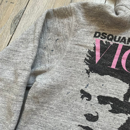 Dsquared2 Vicious Bros SS2019 Hoodie is a grey cotton hoodie made in Italy. It features a hood with drawstring fastening, long sleeves, and ribbed cuffs and hem. The front includes a printed graphic of two outlined figures with a small Dsquared2 logo and pink “Vicious Bros” text above them. The hoodie has intentional distressing throughout the fabric.
