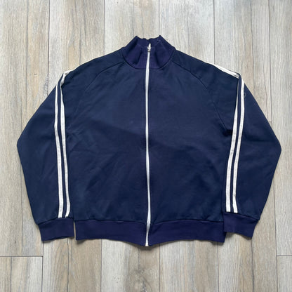 EA Sports 2000s Track Jacket is a navy track jacket with a full white zip closure, white two stripes running down both sleeves, and a fold-down collar. The back features a large stitched EA GAMES circular logo patch.&nbsp;