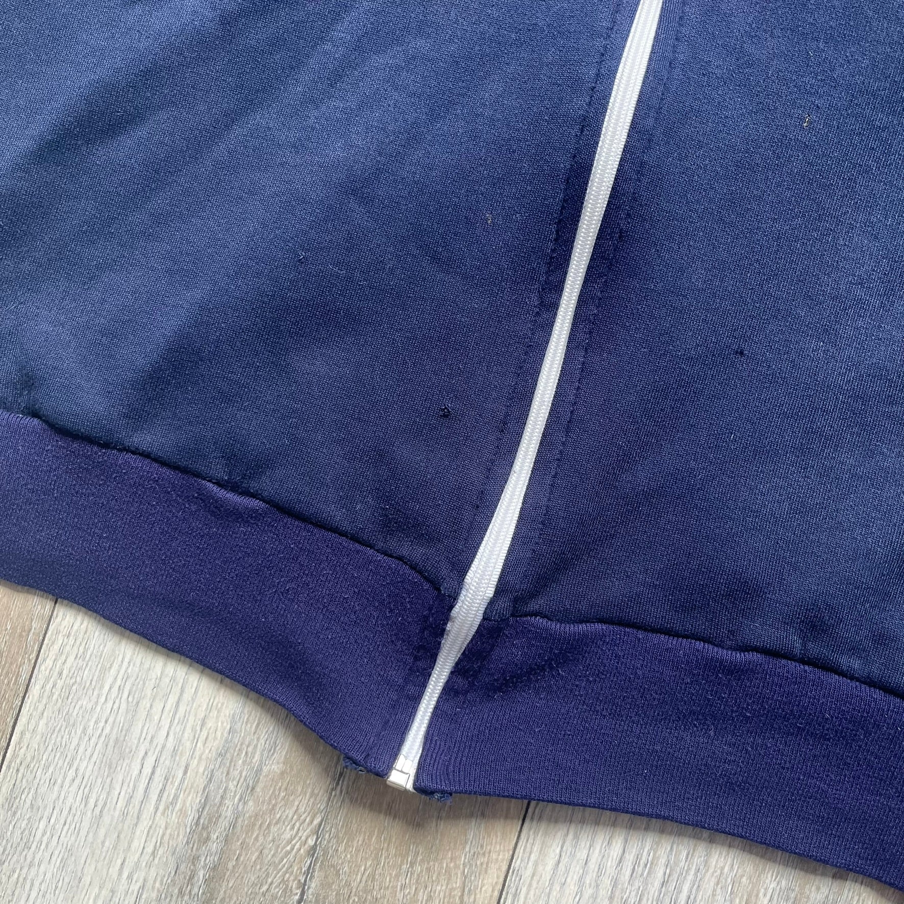 EA Sports 2000s Track Jacket is a navy track jacket with a full white zip closure, white two stripes running down both sleeves, and a fold-down collar. The back features a large stitched EA GAMES circular logo patch.&nbsp;