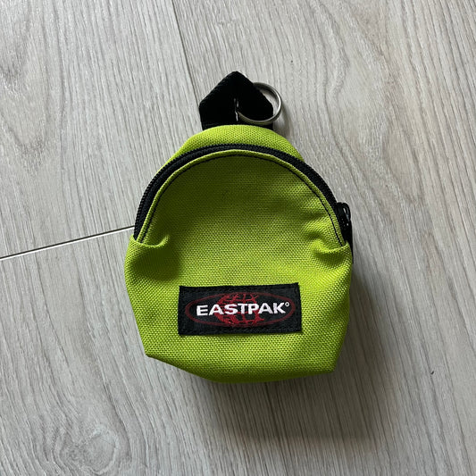 Eastpak’s Mini Green Backpack is a collectible-sized accessory with elastic pack straps. While it can be used as a tiny bag, it’s more often seen as a novelty piece or keychain. A playful twist on the brand’s iconic design.