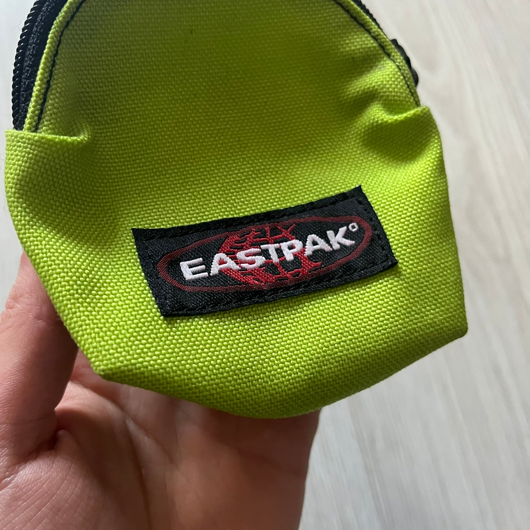 Eastpak’s Mini Green Backpack is a collectible-sized accessory with elastic pack straps. While it can be used as a tiny bag, it’s more often seen as a novelty piece or keychain. A playful twist on the brand’s iconic design.