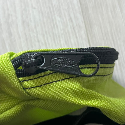 Eastpak’s Mini Green Backpack is a collectible-sized accessory with elastic pack straps. While it can be used as a tiny bag, it’s more often seen as a novelty piece or keychain. A playful twist on the brand’s iconic design.