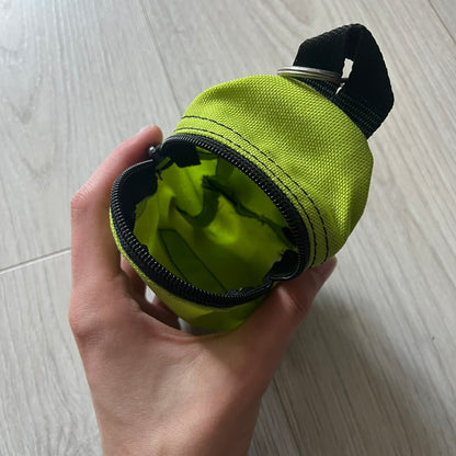 Eastpak’s Mini Green Backpack is a collectible-sized accessory with elastic pack straps. While it can be used as a tiny bag, it’s more often seen as a novelty piece or keychain. A playful twist on the brand’s iconic design.